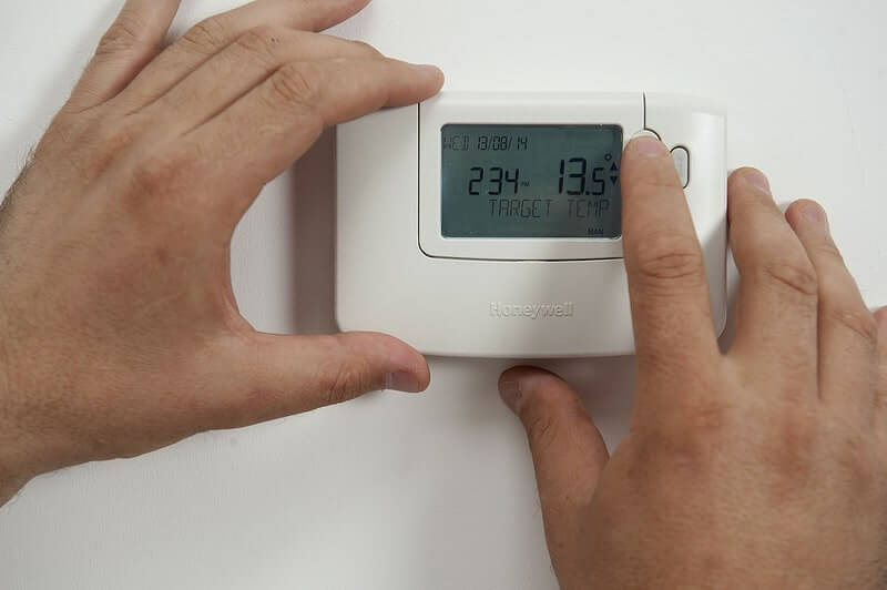 a person adjusting a thermostat