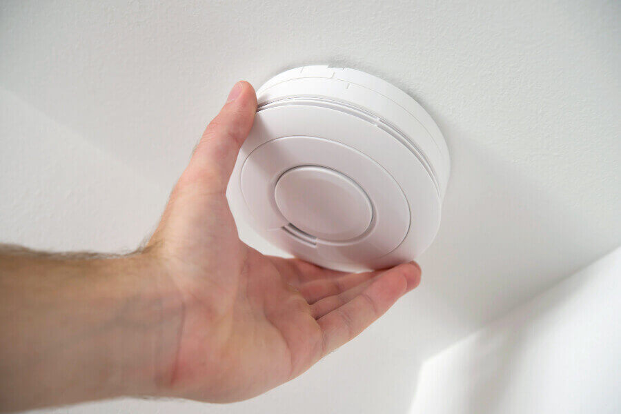 a person inspecting a carbon monoxide detector San Marcos TX